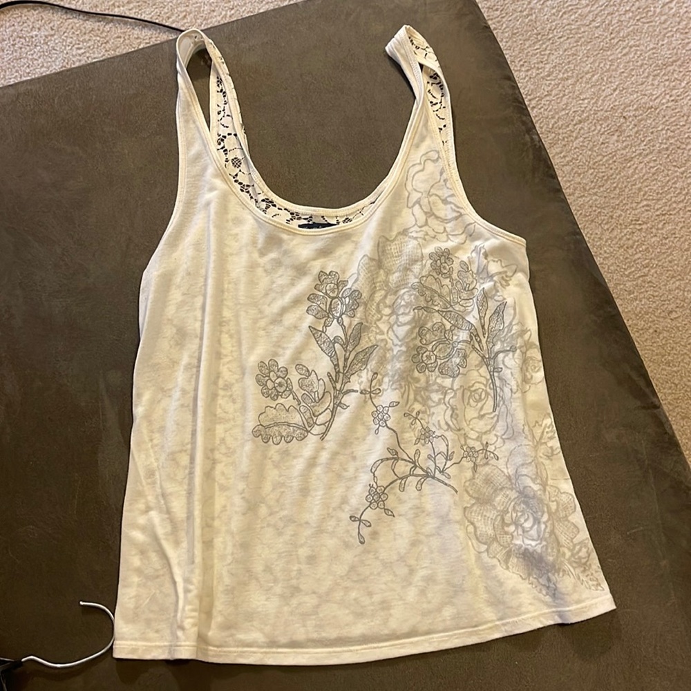 White flowy tank with design on front and lace see through back
